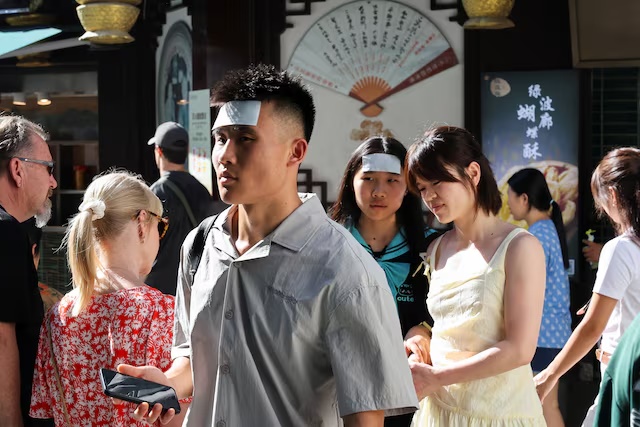 People put cooling gel sheets on their foreheads to cool themselves amid a yellow alert for heat, in Shanghai, China July 4, 2025. REUTERS/Go Nakamura/File Photo 