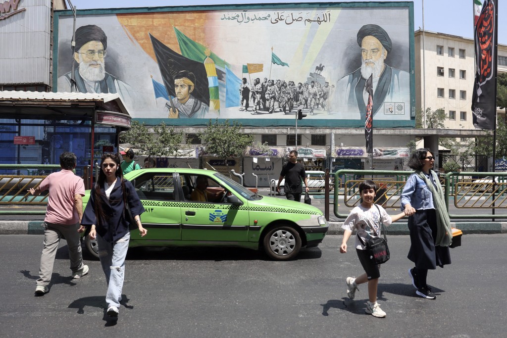 Photo by - / AFP. Iranians walk past a mural depicting late Iranian supreme leaders Ayatollah Ali Khamenei (L) and Ayatollah Ruhollah Khomeini (R) in Tehran on June 18, 2026.