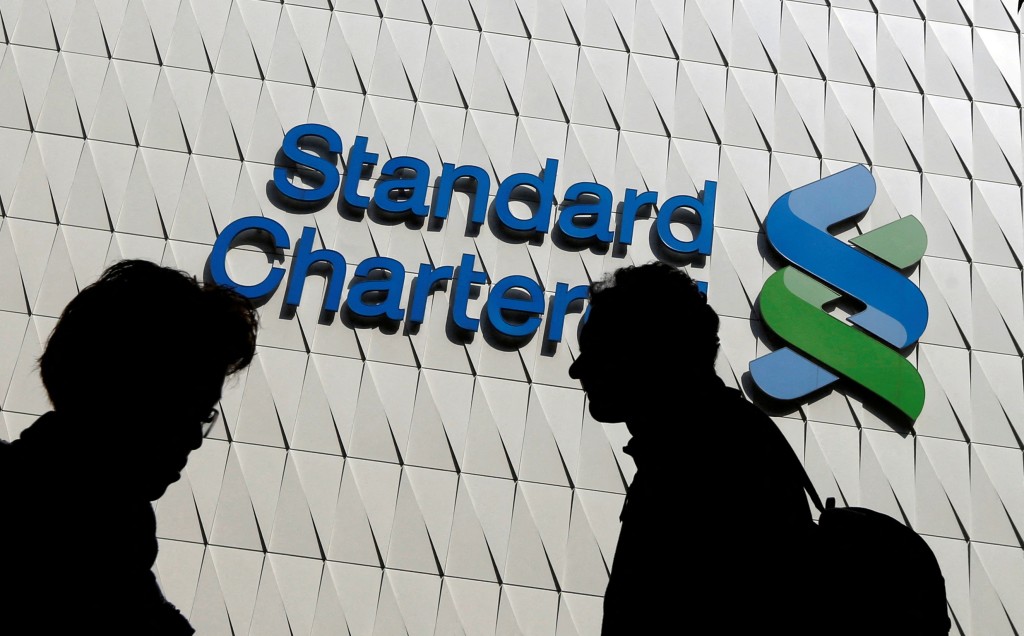 assersby walk in front of the main branch of Standard Chartered in Hong Kong. REUTERS/Bobby Yip