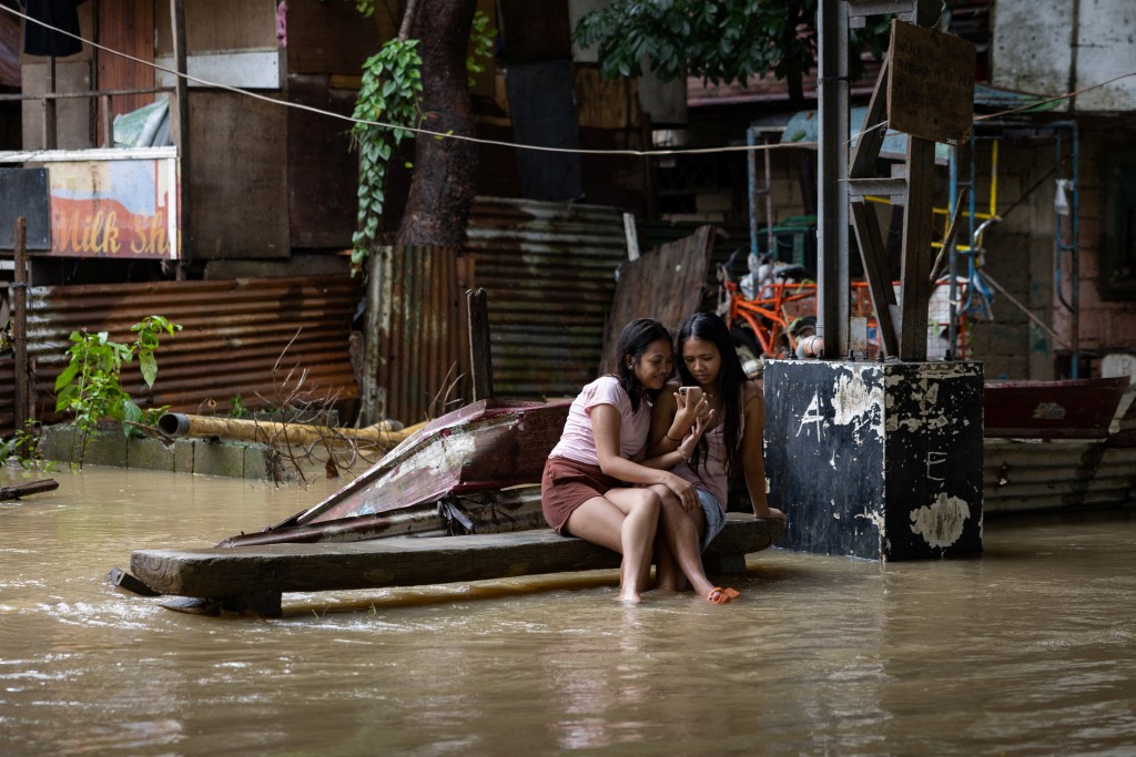Girls sit on a bench at a flooded village amid southwest monsoon rains in Bagong Silangan, Quezon City, Philippines, August 10, 2026. (Reuters)