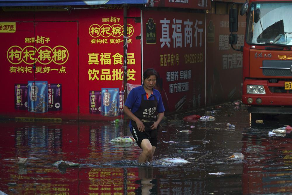 Xing, a shop owner at Yubei Agricultural and Aquatic Products World, walks in floodwaters at the market in Xinxiang in central China's Henan Province, Monday, July 26, 2021. 