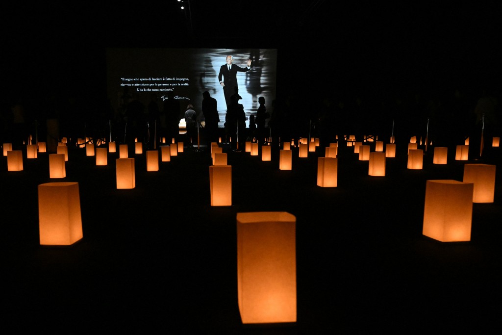 People queue to see the coffin of late Italian fashion designer Giorgio Armani lying-in state for two days at the Armani Theatre in Milan as a picture of him is seen on a screen, on September 6, 2025. Giorgio Armani died on September 4, 2025 at 91. (Photo by Stefano RELLANDINI / AFP)