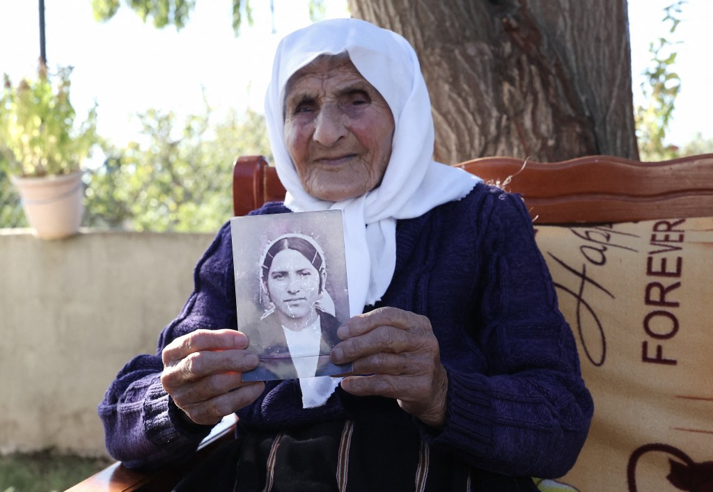 Photo by ADNAN BECI / AFP The 117-year-old Qamile Marra holds a black and white photograph from her youth during an interview with AFP in the garden of her home in the village of Ferras, near Kucove, some 80 kilometres from the capital Tirana on October 3, 2026.
