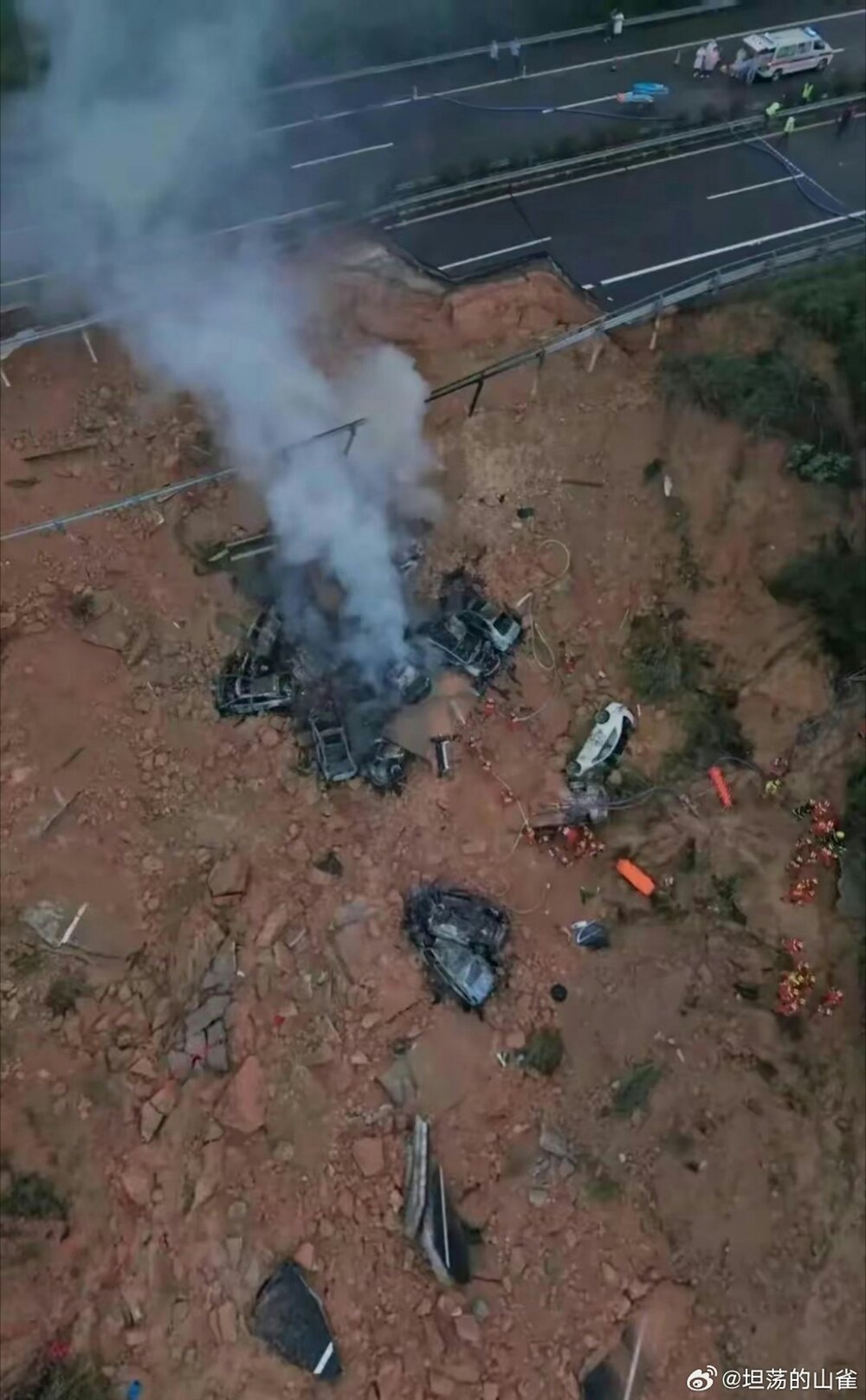 Smoke rises from vehicles that crashed into a pit after part of the highway caved in due to heay rains. Smoke rises from vehicles that crashed into a pit after part of the highway caved in due to heay rains.