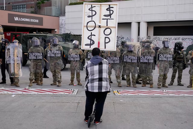 National Guard members stand guard outside the Edward R. Roybal Federal Building as a demonstrator takes part in a protest against federal immigration sweeps, in Los Angeles, California, U.S., June 12, 2025. REUTERS/David Ryder