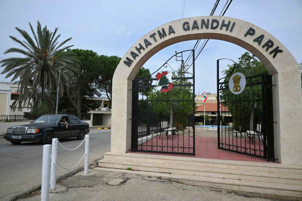 A car drives past the Indian Leader Mahatma Ghandi's park in the southern Lebanese border village of Ibl Al Saqi, displays a number of pants on a hanger at his shop on October 13, 2026.