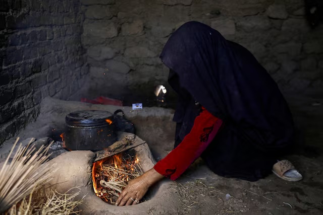 An Afghan woman lights fire to cook food at a makeshift kitchen in Markhor-e-Sufla village, Herat, Afghanistan October 26, 2024. REUTERS/Sayed Hassib