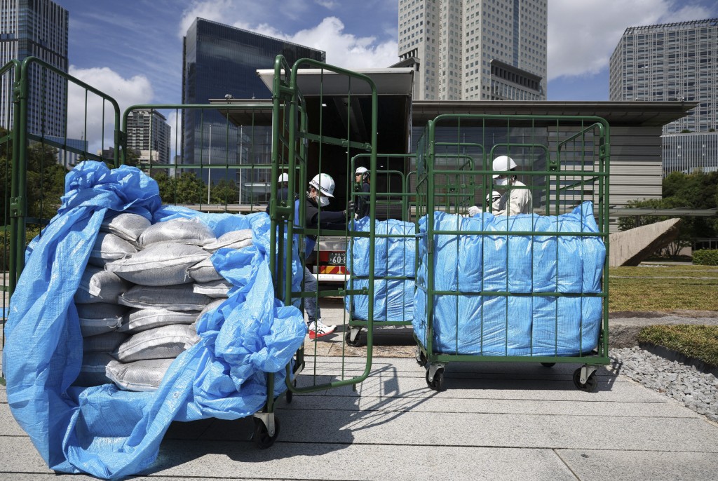 Workers unload bags of soil removed during decontamination following the Fukushima Daiichi nuclear power plant accident, at the Prime Minister's office in Tokyo on July 19, 2025. (Photo by JIJI PRESS / AFP) / JAPAN OUT