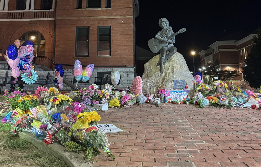 Photo by A.M. STEWART / AFP The bronze statue of late US singer-songwriter Dolly Parton is seen surrounded by flowers and balloons placed by fans outside the Sevier County Courthouse in downtown Sevierville, Tennessee on August 25, 2026.