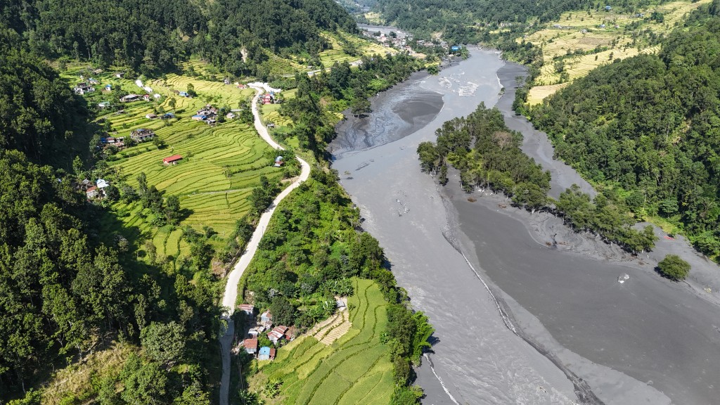 Photo by PRAKASH MATHEMA / AFP  An aerial view shows muddy water flowing through the Budhi Gandaki river, separating Nepal's Gorkha (L) and Dhading districts on October 14, 2026, in the aftermath of a flash flood caused by a dry landslide.