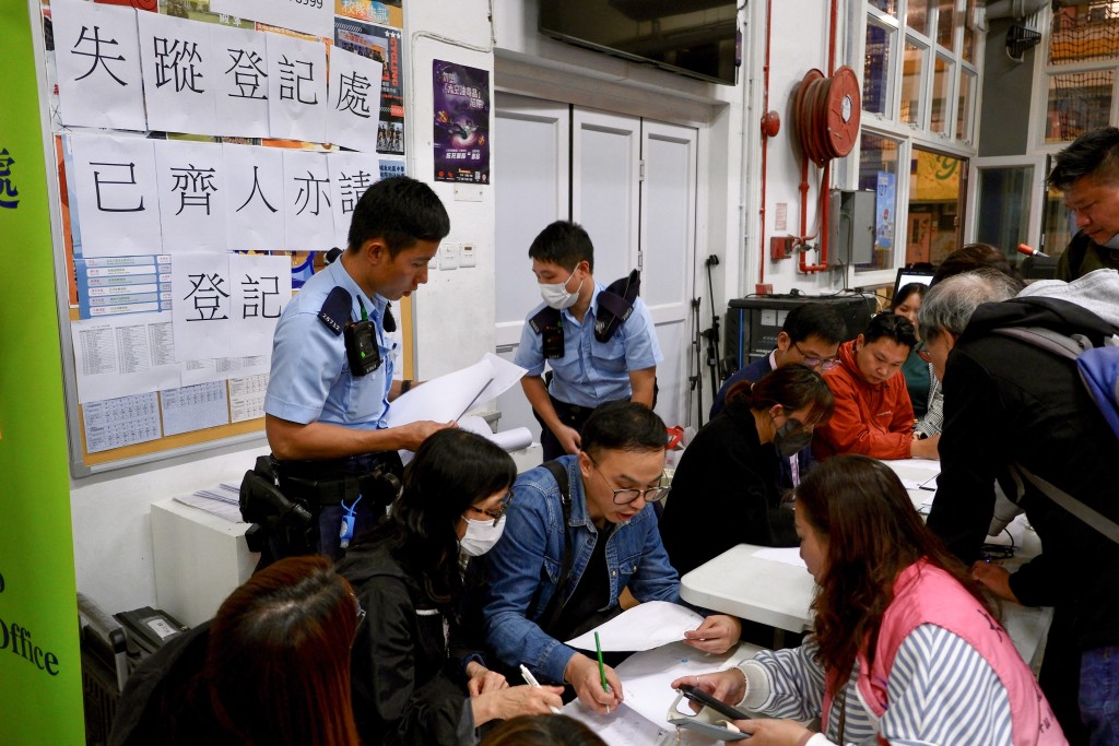Photo by TOMMY WANG / AFP  Some residents report their family members' situations to the police and officials at a temporary shelter near the Wang Fuk Court residential estate in Hong Kong's Tai Po district on November 26, 2025.