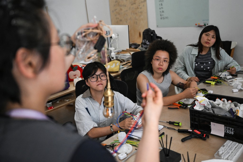 Photo by PEDRO PARDO / AFP  This picture taken on June 28, 2026 shows instructor Wu Shuang (L) giving an electricity course to a group of women at the Mulan Build workshop in Hangzhou, in eastern China's Zhejiang province.