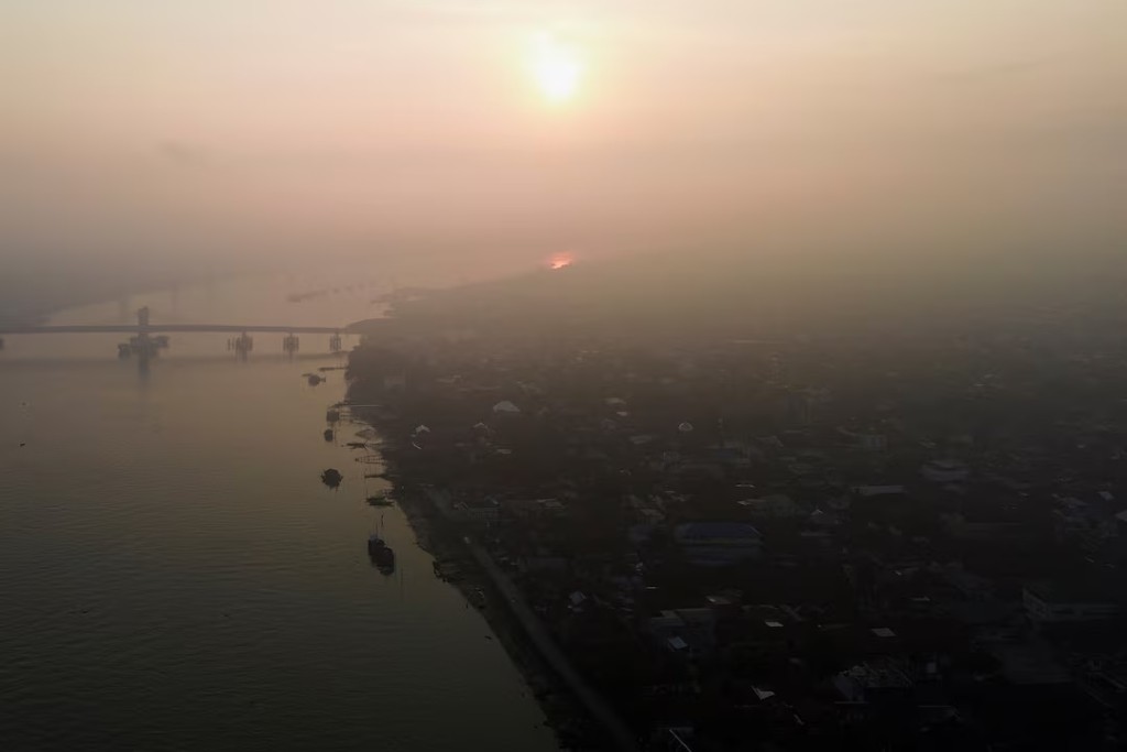 A drone view shows a residential area along the Musi river as smog covers it due to recent wildfires in Palembang, South Sumatra province, Indonesia, August 11, 2026. REUTERS/Abriansyah Liberto 