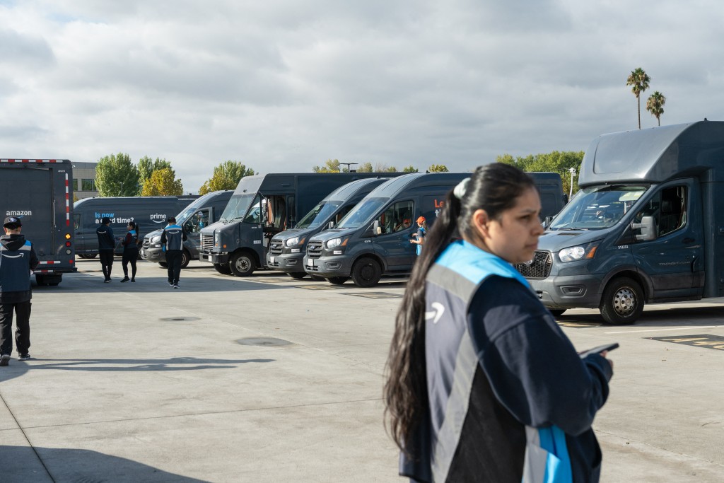 Drivers walk to the vehicles for their delivery shifts at Amazon’s DUR3 Delivery Station in Milpitas, California on October 22, 2025. (Photo by Laure Andrillon / AFP)