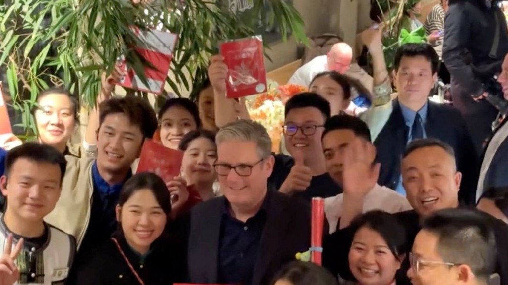 Keir Starmer poses with a gift he accepted from a staff in Beijing. Reuters