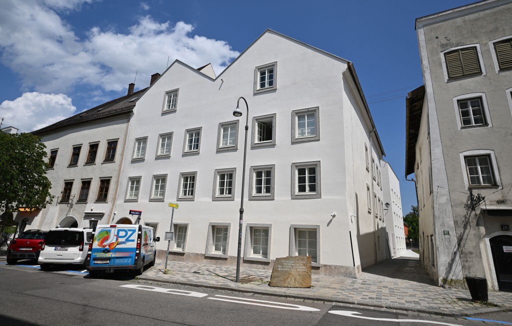 Photo by KERSTIN JOENSSON / AFP  A memorial stone reading "For Peace, Freedom and Democracy - Never Again Fascism - Millions of Dead Warn" stands in front of the birth house of former German dictator Adolf Hitler that is turned into a police station, in Braunau am Inn, Austria on July 16, 2026.