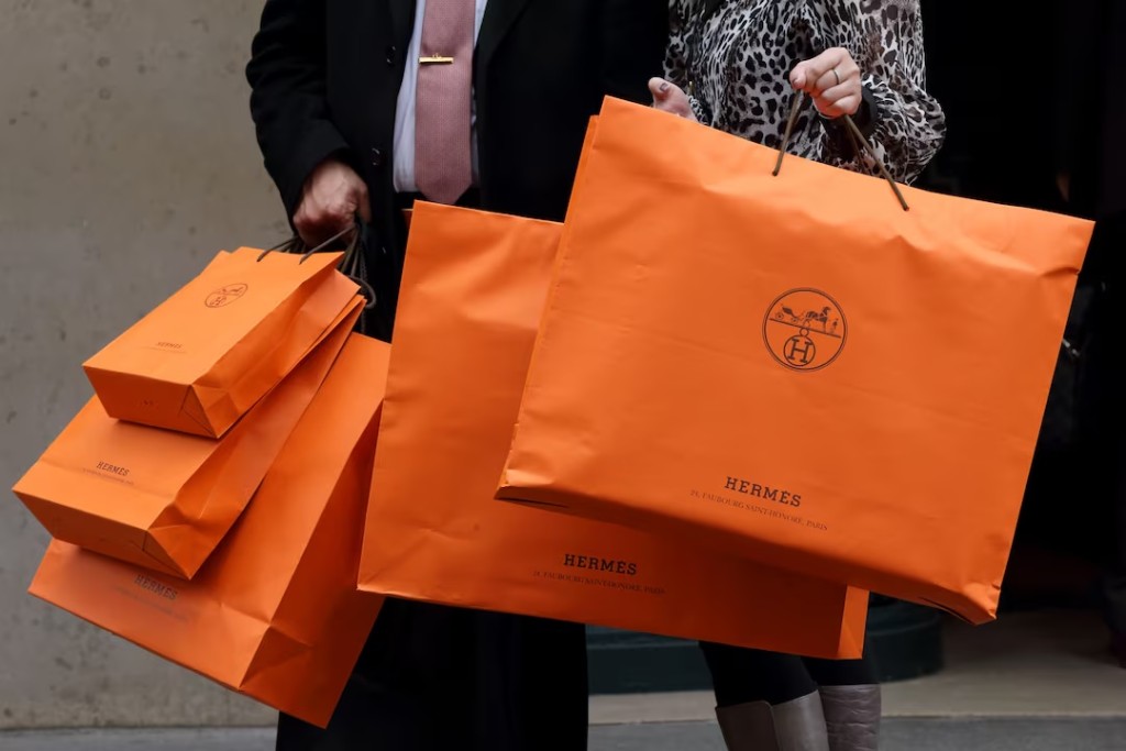 A couple walk with Hermes shopping bags as they leave an Hermes store in Paris March 21, 2013. REUTERS/Philippe Wojazer