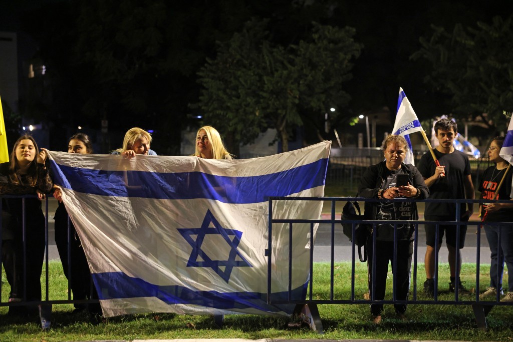 People watch as vehicles transporting the bodies of four hostages handed over following a ceasefire and prisoner exchange deal between Israel and Palestinian factions in Gaza arrive at the National Center for Forensic Medicine in Tel Aviv on October 15, 2025.  Photo by AHMAD GHARABLI / AFP
