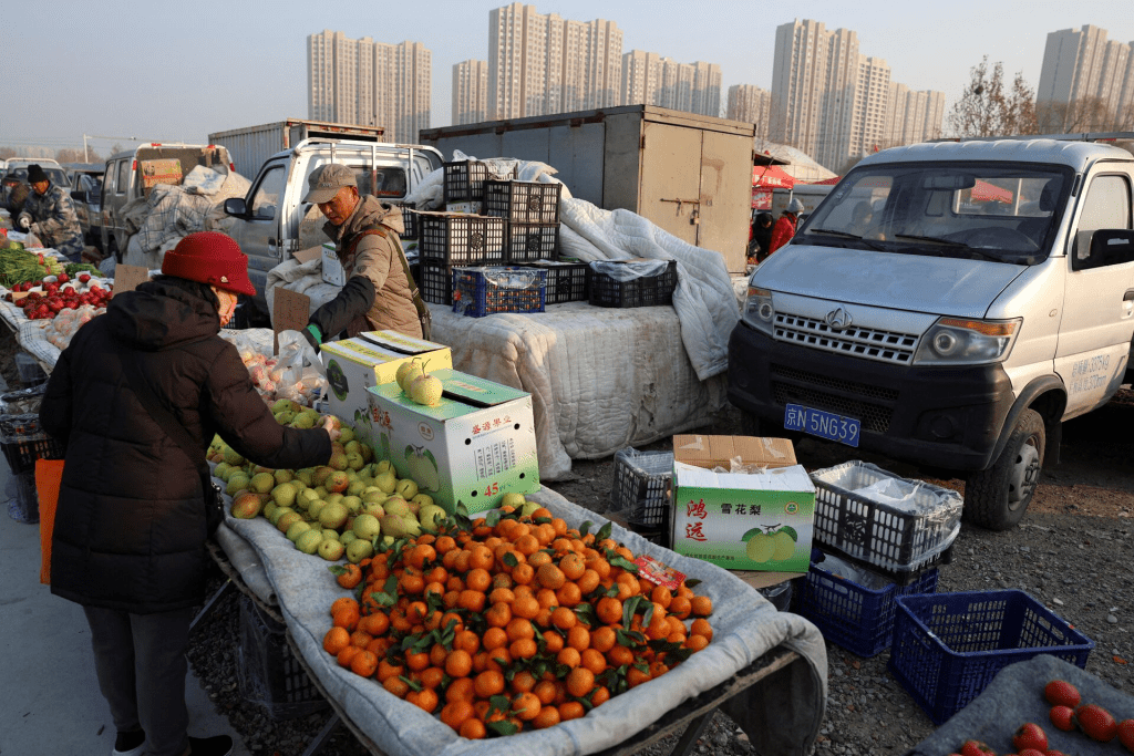A fruit vendor attends to a customer at an outdoor market in Beijing, China January 12, 2024. REUTERS/Florence Lo/File Photo 