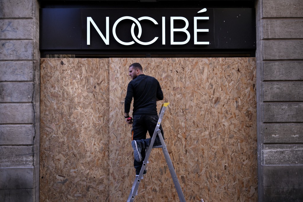 A worker installs wooden panels to French beauty retailer Nocibe's store along the Saint-Catherine shopping street in Bordeaux, southwestern France on October 30, 2026 a day ahead of new nationwide protests over the soaring cost of living and inequality. (Photo by Christophe ARCHAMBAULT / AFP)