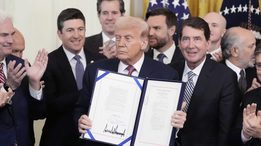 President Donald Trump holds up the GENIUS Act, a bill that regulates stablecoins, a type of cryptocurrency, after he signs the bill in the East Room of the White House, Friday, July 18, 2025, in Washington. (AP Photo/Alex Brandon)