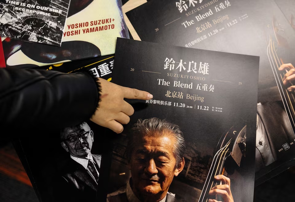 A woman points to an advertisement poster for a cancelled concert by Japanese musician Yoshio Suzuki before the organisers' interview with Reuters in Beijing, China, November 21, 2025. REUTERS/Maxim Shemetov