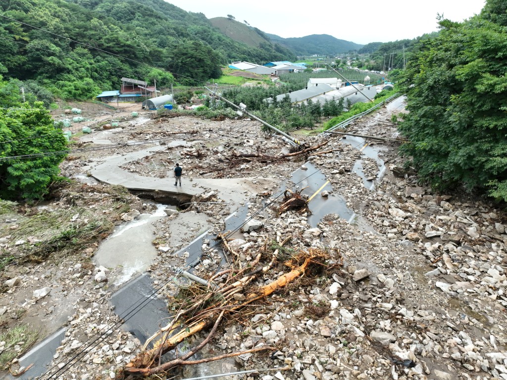 A man stands among stones and the soil scattered after the landslide caused by torrential rain in Yesan, South Korea, July 17, 2025. (Reuters)