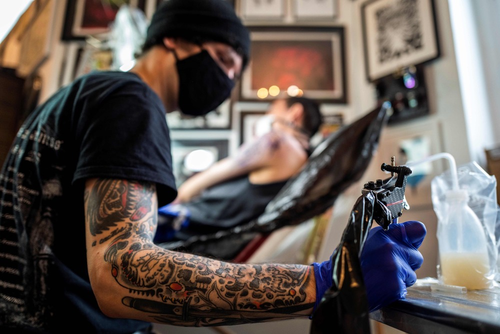 A tattoo artist dips his tattoo machine in ink as he tattooes a customer at a tattoo parlour in Berlin on June 12, 2020. (AFP) A tattoo artist dips his tattoo machine in ink as he tattooes a customer at a tattoo parlour in Berlin on June 12, 2020. (AFP)