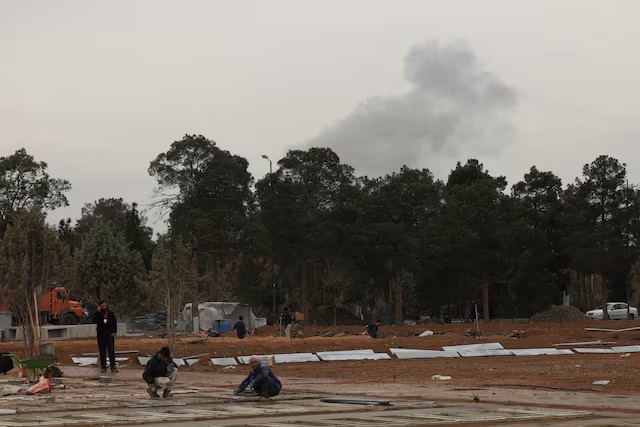 People work during an expansion of a cemetery, as smoke following airstrikes rises behind the Behesht-e Zahra cemetery, amid the U.S.-Israeli conflict with Iran, in Tehran, Iran, March 16, 2026. REUTERS/Alaa Al-Marjani 