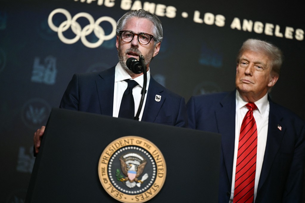 Photo by BRENDAN SMIALOWSKI / AFP  US President Donald Trump (R) looks on as LA 2028 Chairman Casey Wasserman (L) speaks during an event on creating a White House 2028 Olympics task force in the South Court Auditorium of the White House in Washington, DC, on August 5, 2025.