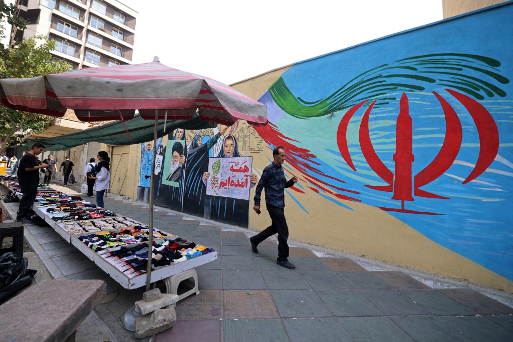 A pedestrian walks past a wall mural along a street in downtown of Tehran on August 31, 2026. (AFP)