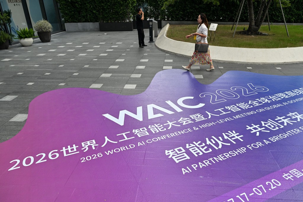 A woman walks past signage for the World Artificial Intelligence Conference (WAIC) in Shanghai on July 16, 2026. (Photo by Hector RETAMAL / AFP)