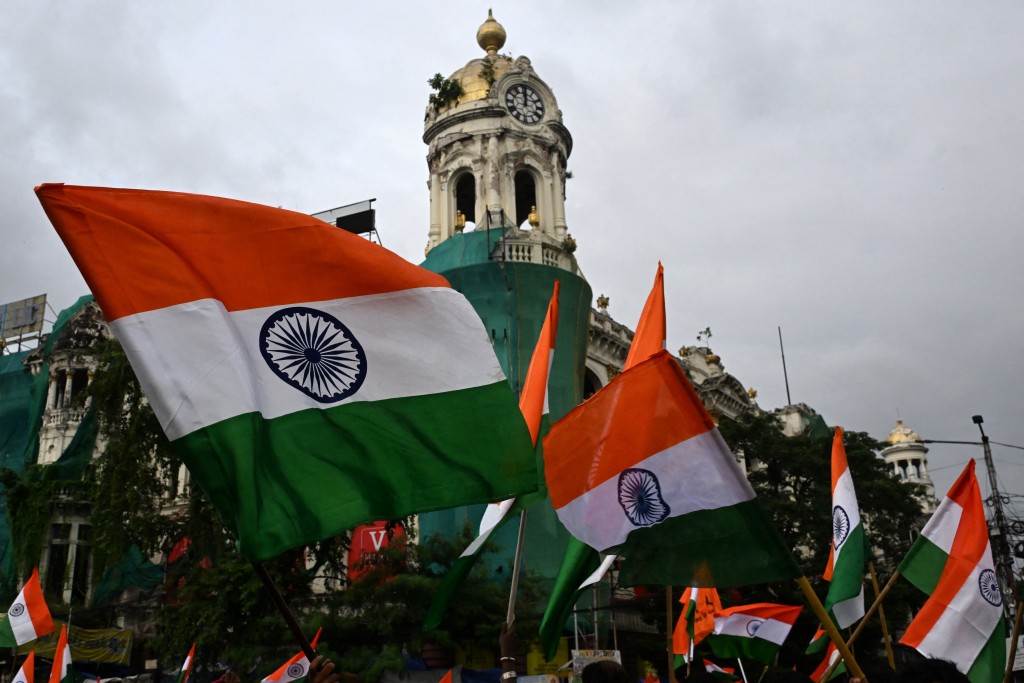 Bharatiya Janata Party (BJP) activists wave India's national flags during a rally in Kolkata on July 27, 2026 to protest against the Cockroach Janta Party (CJP) demanding the resignation of India's Education Minister Dharmendra Pradhan over alleged NEET exam irregularities. (Photo by Dibyangshu SARKAR / AFP)