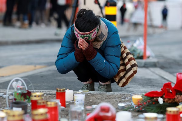 A person pays tribute next to the candles placed for the victims outside the "Le Constellation" bar, after a fire and explosion during a New Year's Eve party where several people died and others were injured, according to Swiss police, in the upscale ski resort of Crans-Montana in southwestern Switzerland, January 2, 2026. REUTERS/Stephanie Lecocq 