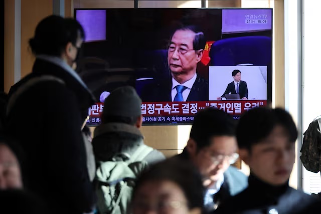 People watch a TV broadcasting a news report on South Korea's Seoul Central District Court ruling on charges against former Prime Minister Han Duck-soo for engaging in a key action of insurrection concerning ex-President Yoon Suk Yeol's declaration of martial law in December 2024, in Seoul, South Korea, January 21, 2026. REUTERS/Kim Hong-Ji