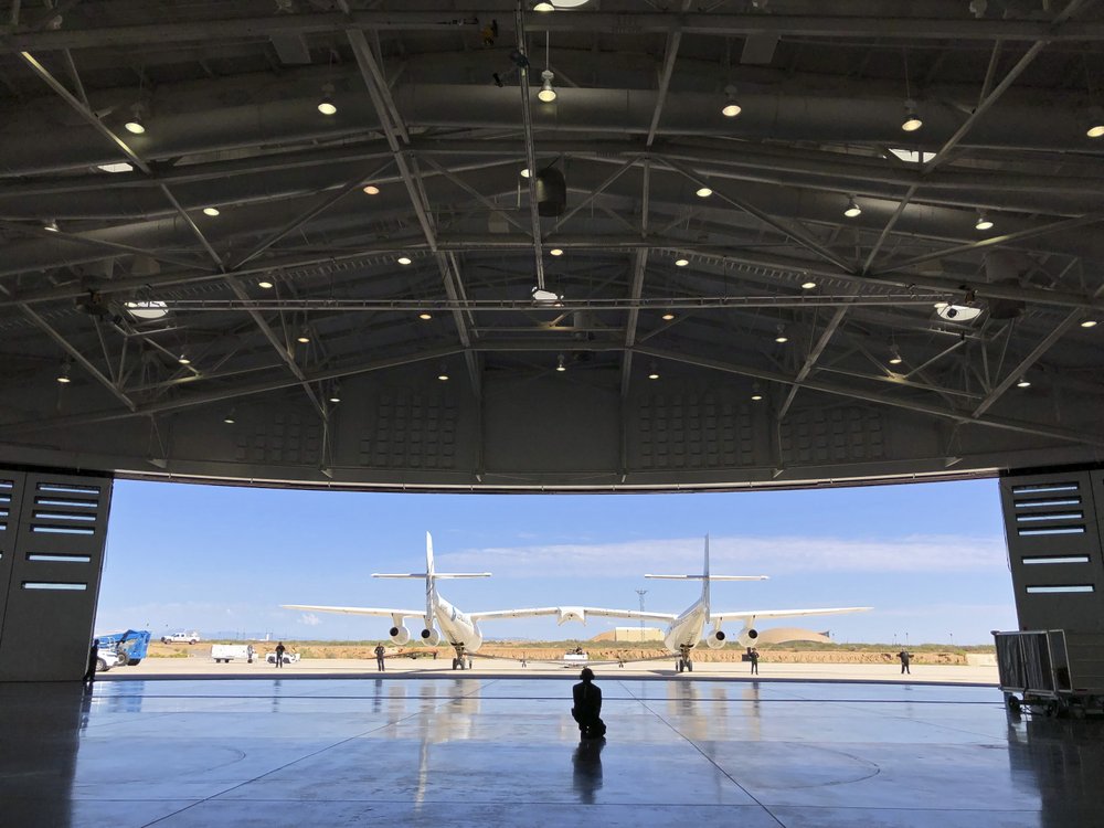 In this August 15, 2019 file photo, Virgin Galactic ground crew guide the company's carrier plane into the hangar at Spaceport America following a test flight over the desert near Upham, New Mexico. In this August 15, 2019 file photo, Virgin Galactic ground crew guide the company's carrier plane into the hangar at Spaceport America following a test flight over the desert near Upham, New Mexico.