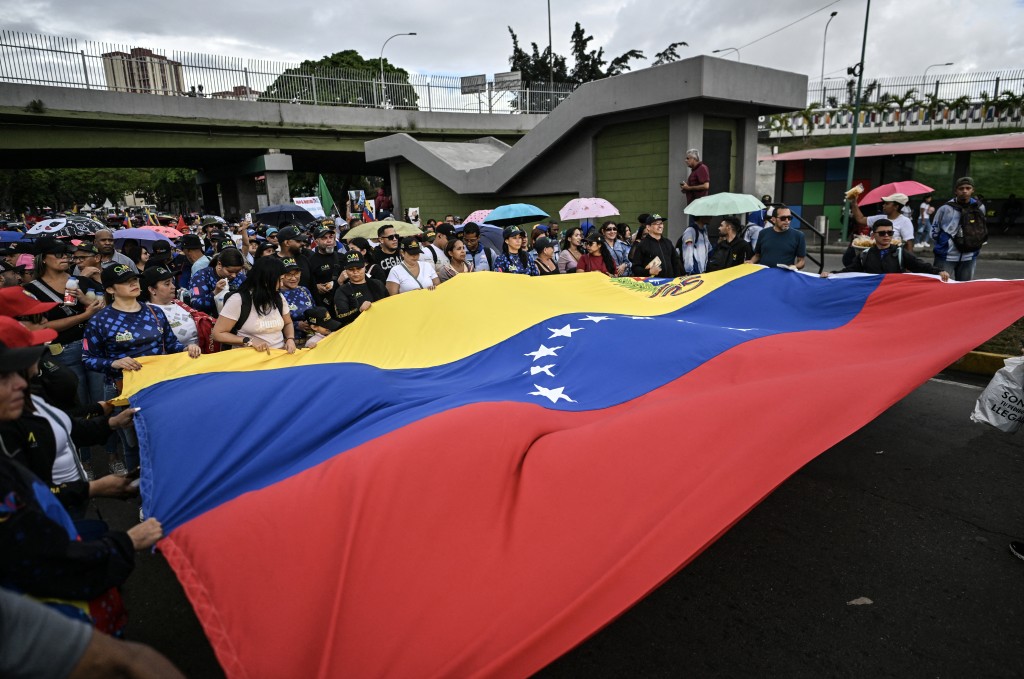 Demonstrators wave a giant Venezuelan flag during a rally in support of ousted Venezuela's President Nicolas Maduro in Caracas on January 10, 2026. (AFP)