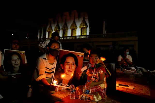 Migrants protesting against the military junta in Myanmar hold a picture of leader Aung San Suu Kyi, during a candlelight vigil at a Buddhist temple in Bangkok, Thailand, March 28, 2021. REUTERS/Jorge Silva