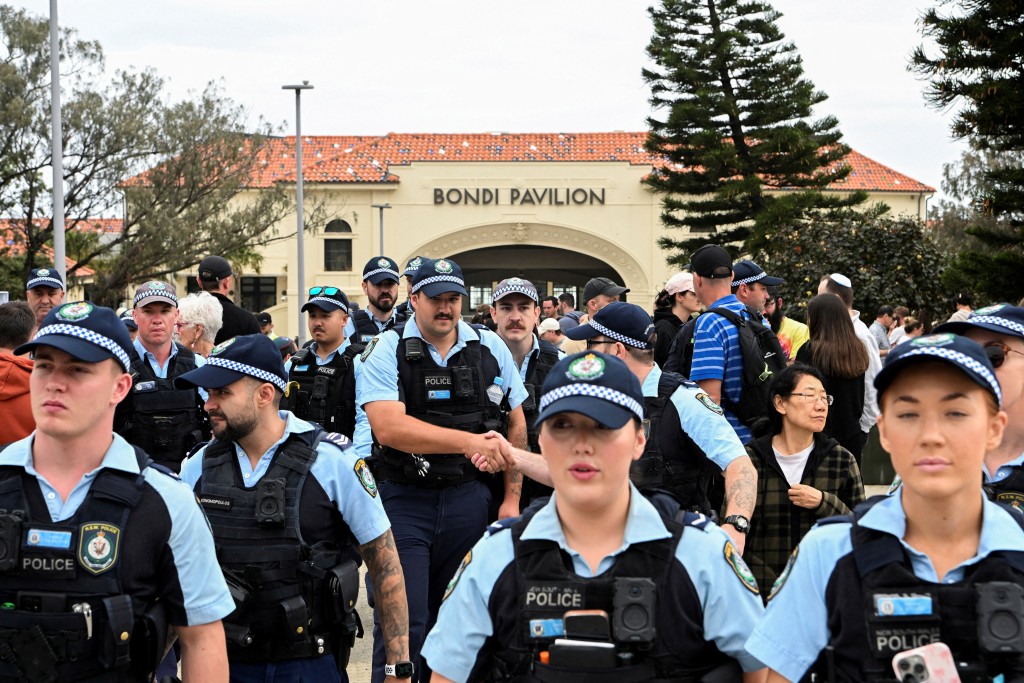 FILE PHOTO: Police officers gather near Bondi Beach pavilion, at the floral memorial to honour the victims of a mass shooting that targeted a Hanukkah celebration on Sunday, at Bondi Beach, in Sydney, Australia, December 16, 2025. REUTERS/Flavio Brancaleone/File Photo