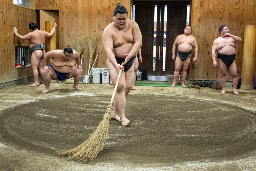 This picture taken on January 8, 2026 shows a sumo wrestler sweeping the sacred clay ring "dohyo" during practice at the Kise sumo stable in Tokyo.   Photo by MATHIAS CENA / AFP