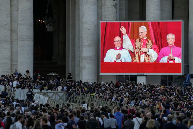 People watch as newly elected Pope Leo XIV, Cardinal Robert Prevost of United States, shown on screen, appears on the balcony of St. Peter's Basilica, as seen from Rome, Italy May 8, 2025. REUTERS/Alkis Konstantinidis