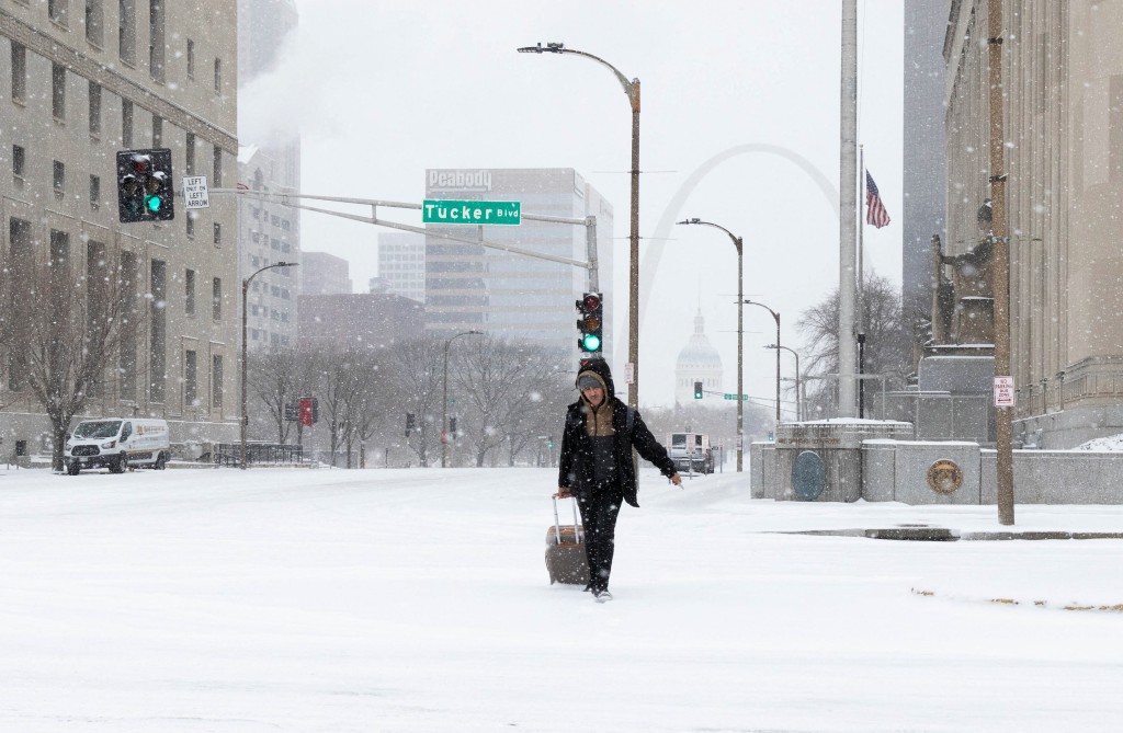 A pedestrian pulls a rolling suitcase through snow‑covered downtown streets as winter weather continues to blanket St. Louis, Missouri, U.S., January 24, 2026. (Reuters)