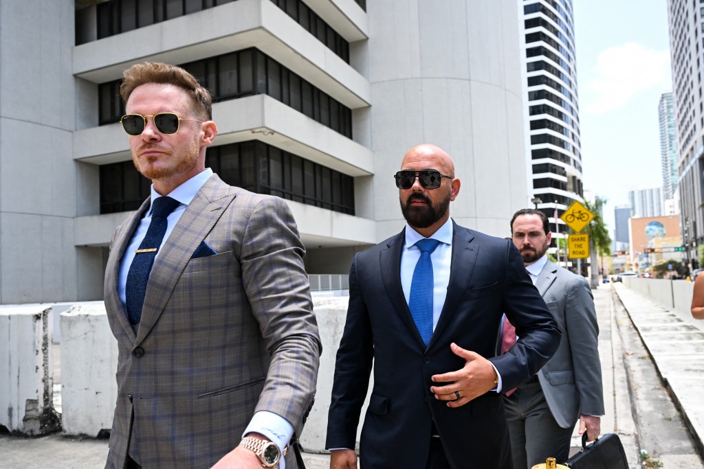 Photo by CHANDAN KHANNA / AFP Joseph D. McBride (C), attorney for Andrew Tate and Tristan Tate, and Justin Waller (L) depart following a hearing for the Tate brothers at the C. Clyde Atkins US Courthouse in Miami, Florida, on July 20, 2026.