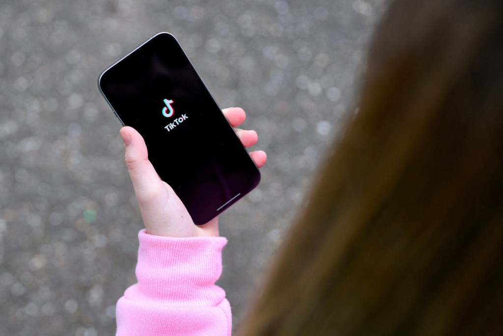 A teenager poses for a picture with a phone displaying the TikTok logo, in Bonn, Germany, February 20, 2026. REUTERS