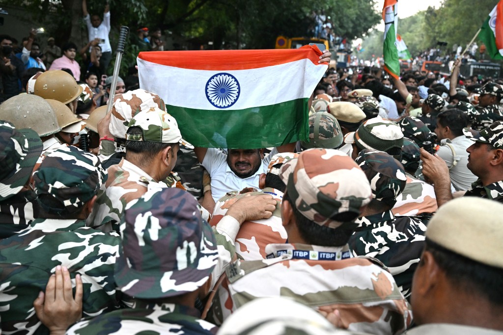 Photo by SAJJAD HUSSAIN / AFP  A supporter of India's opposition Congress party holds the country's national flag as he scuffles with security personnel during a protest demanding the resignation of the nation's Chief Election Commissioner Gyanesh Kumar over alleged voter roll irregularities linked to the "special intensive revision" (SIR), in New Delhi on October 12, 2026.