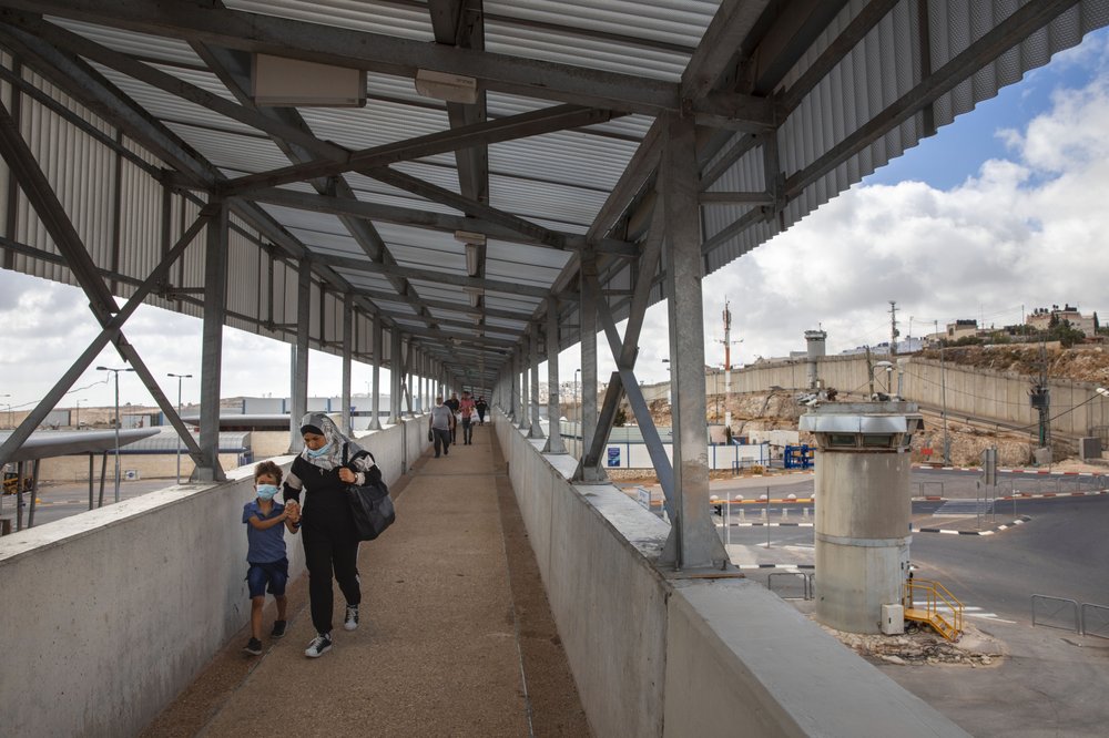 In this Friday, June 19, 2020 photo, Palestinians cross a bridge at Qalandia checkpoint between the West Bank city of Ramallah and Jerusalem. In this Friday, June 19, 2020 photo, Palestinians cross a bridge at Qalandia checkpoint between the West Bank city of Ramallah and Jerusalem.