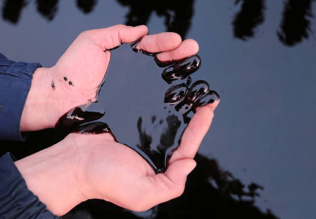 A man scoops up oil with his hands in this illustration taken at the Airankol oil field in the Atyrau Region, Kazakhstan, April 1, 2025. REUTERS/Pavel Mikheyev/Illustration 