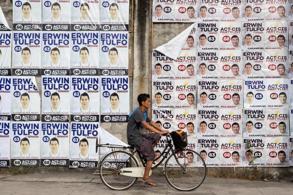  A man bikes past a wall of campaign posters for senatorial candidate Erwin Tulfo on the first day of the campaign period for the May 12 midterm elections, in Manila, Philippines, February 11, 2025. REUTERS/Eloisa Lopez