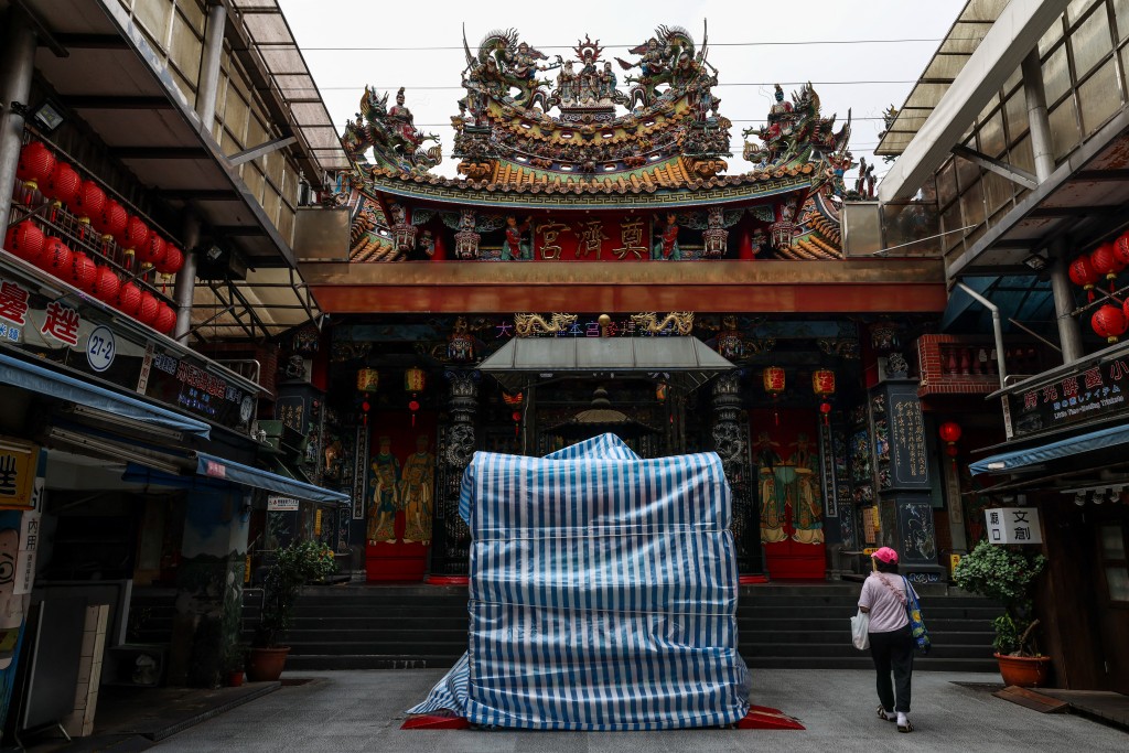 TOPSHOT - Statues outside Keelung's Dianji Temple are covered with protective tarpaulins ahead of the arrival of Typhoon Bavi in Keelung on July 10, 2026 (Photo by I-Hwa Cheng / AFP)