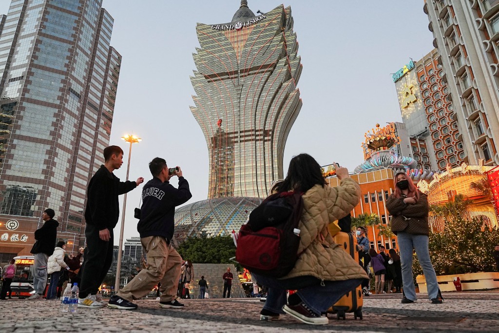 Visitors pose for photos outside the Grand Lisboa casino operated by SJM Holdings during Lunar New Year in Macau, China, January 24, 2023. REUTERS